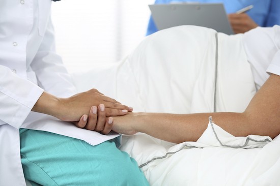 Friendly female medicine doctor’s hands holding pregnant woman’s hand